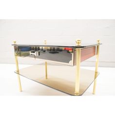 a glass and brass coffee table with two drawers on each side, in the shape of a rectangle