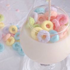 a glass filled with cereal and doughnuts on top of a white tablecloth