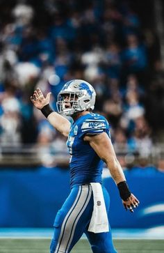 a football player throwing a ball in the air with his hand out to catch it