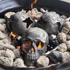 two skulls are sitting in a bowl full of rocks and coals with flames coming out of them