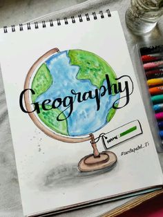 an open notebook with the words geography on it next to colored crayons