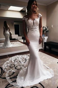 a woman in a white wedding dress standing on a carpeted area with a mirror behind her