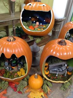 three pumpkins are sitting on the ground with fake plants and other decorations around them