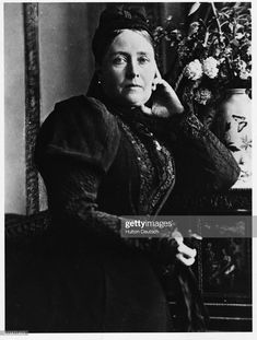 an old black and white photo of a woman sitting in front of a vase with flowers