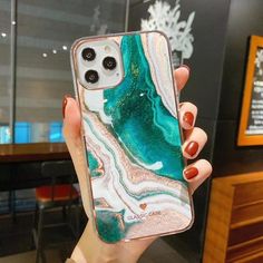 a woman holding up her phone case with green and white marble