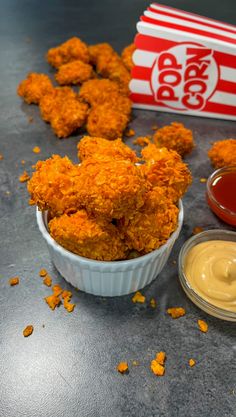 some fried food is in a bowl next to a box of mustard and ketchup