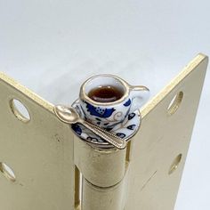 a cup and saucer sitting in the middle of a metal door hinges