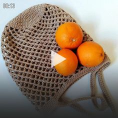 three oranges sitting on top of a crocheted bag