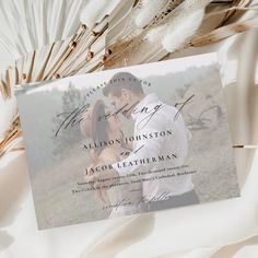 a wedding card with an image of a couple on it and feathers in the background