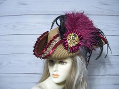 One-of-a-kind dark tan faux straw nice quality pirate hat with burgundy and tan embellishment, burgundy satin cocarde with a large sparkly jewel accent, a metal pirate's coin on the other side and these beautiful long flowing all natural coque feathers with burgundy ostrich feathers overlay. The coque feathers are all natural, so they are not perfect, please keep this in mind. Please measure your head, this hat is 22.5" for the inside circumference with a built-in hat sizer. Just cinch and tie. I cannot make the circumference bigger. Check out my other pirate hats and other goodies Please let me know if you have any questions All sales are FINAL, no returns or exchanges please keep this in mind before purchasing. International buyers: Please know that you will be held responsible for any C Pirate Hat Aesthetic, Tricorn Hat, Pirate Coins, Hat Aesthetic, Pirate Hat, Pirate Hats, Pirate Woman, Halloween Hats, Costume Hats