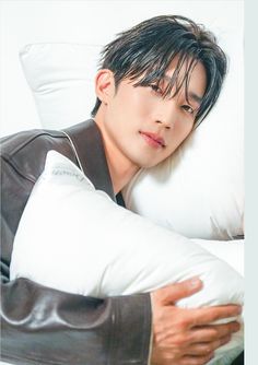 a young man laying on top of a pillow next to a pillow with his arm wrapped around the pillow