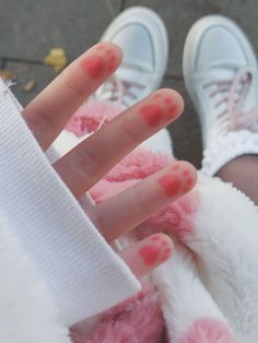 a person with red nail polish on their nails and white shoes is holding up her hand