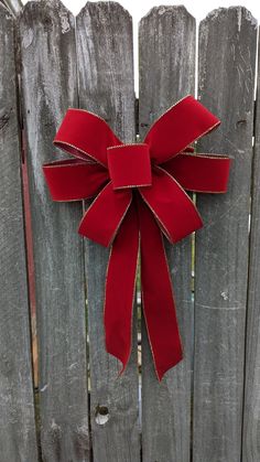 a red bow hanging on the side of a wooden fence