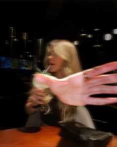 a woman sitting at a table with her hand reaching out to grab something in front of her