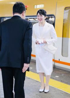 a woman in a white dress is walking towards a man in a black suit and tie