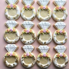 decorated cookies arranged in the shape of rings with flowers and leaves on them, sitting on a pink surface