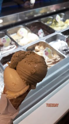 an ice cream sundae is being held up by someone's hand in front of some gelato