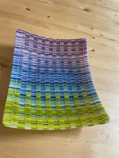 a multicolored glass plate sitting on top of a wooden table