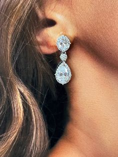 a woman's ear with two pear shaped diamond earrings on top of her head