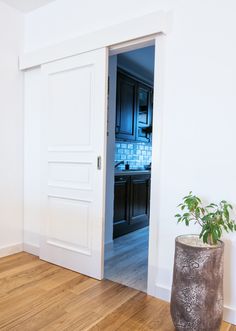 an open door leading to a kitchen and living room with hardwood floors in the foreground