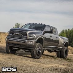 a large gray truck driving down a dirt road