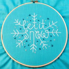 a cross stitch pattern with the words let it snow written in white on a blue background