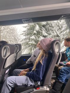 two people sitting in the back of a bus on a snowy day