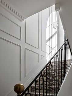 the stairs are lined with black iron railings and handrails, leading up to an arched window