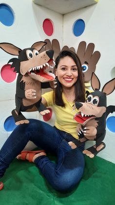 a woman sitting on the ground with three fake animals in front of her and smiling at the camera