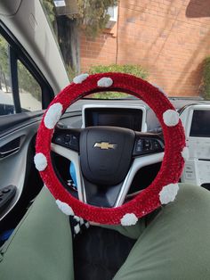 the steering wheel cover is decorated with red and white pom - poms