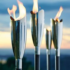 four metal torches with flames burning in the middle and on each one's sides