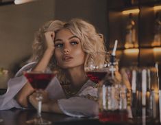 a woman sitting at a bar with two glasses of wine in front of her,