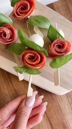 a person is holding some food on a stick with leaves and flowers in the middle