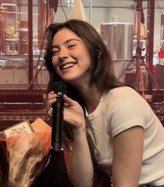 a woman sitting on the floor holding a microphone and smiling at someone in front of her