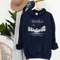 Alaska The Last Frontier Hoodie, FREE SHIPPING, Alaska Sweatshirt Cozy sweatshirt is made from a great 50/50 cotton and polyester blend - it feels so soft, plush and warm! Great for last minute gifts and fans of all things comfortable! Please see our size chart and colors (available colors and sizes may vary, please reach us to find out currently available colors and sizes). With good care, this shirt will last ages and ages and always feel soft.  Please let us know if you have any question before ordering, we will do our best to address your inquiry as quickly as possible. THANKS FOR CHOOSING US! Winter Crew Neck Tops For Adventure, Pre-shrunk Relaxed Fit Hoodie, Hooded Graphic Print Top For Outdoor Activities, Hooded Graphic Print Tops For Outdoor, Letter Print Crew Neck Hoodie For Adventure, Crew Neck Letter Print Hoodie For Adventure, Pre-shrunk Long Sleeve Tops For Outdoor, Relaxed Fit Hoodie For Outdoor, Crew Neck Cotton Hoodie For Hiking