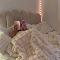 a person laying in bed with a book on top of their head and blankets over them