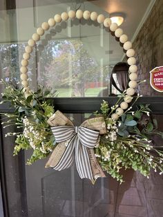 a wreath hanging on the front door decorated with white and green flowers, greenery and beads