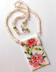 a beaded necklace with flowers on it and a small pendant hanging from the end