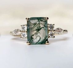 a green and white stone ring with diamonds