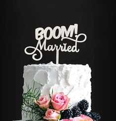 a white cake with flowers on top and a sign that says boom married