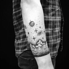 a person with a tattoo on their arm and the image of planets in the sky