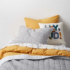 an unmade bed with yellow and white pillows