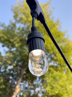 a light that is hanging from the side of a pole with trees in the background