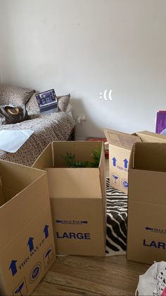 several boxes are stacked on the floor in front of a couch and bed with pillows