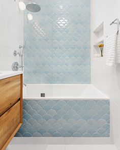 a bathroom with blue and white tiles on the walls, floor, and bathtub