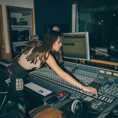 a woman in a recording studio is working on her sound mixing equipment and looking at the screen