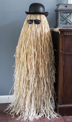 a hat and sunglasses are on top of a long, shaggy wig in front of a dresser