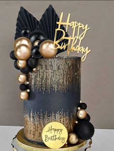 a black and gold birthday cake with balloons on it's side, happy birthday