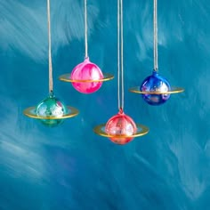 three colorful glass ornaments hanging from strings against a blue background