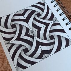 a spiral design is shown on top of a notebook with pen and paper next to it